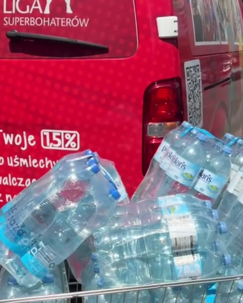 Wózek pełen zgrzewek wody butelkowanej przy czerwonym busie Ligi Superbohaterów — tak wyglądało zaopatrzenie oddziału przed montażem